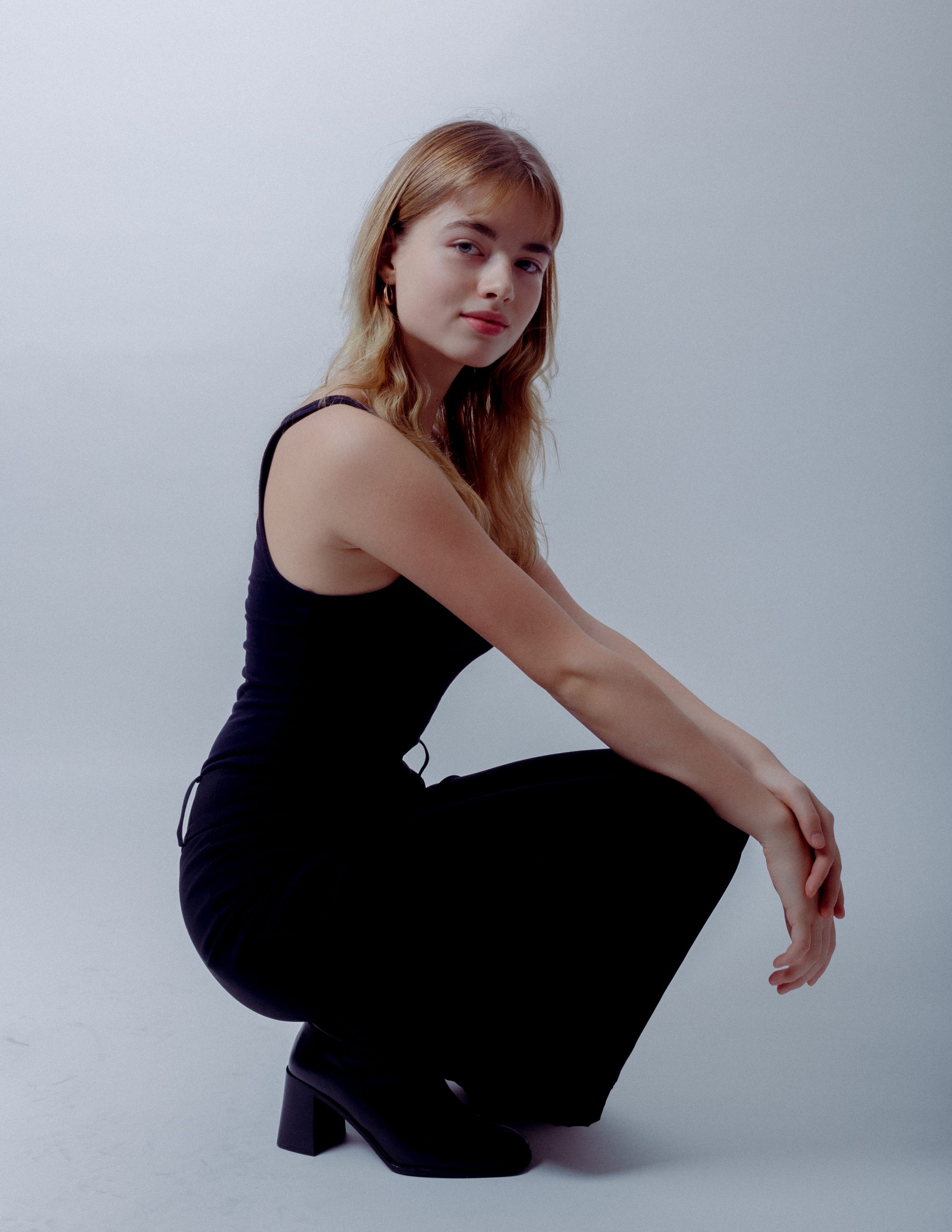 Natalia Lidwa, cała postać, kuca bokiem, ubrana na czarno spodnie, koszulka na ramiączkach